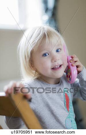 Stock Image - Toddler playing with toy phone. Fotosearch