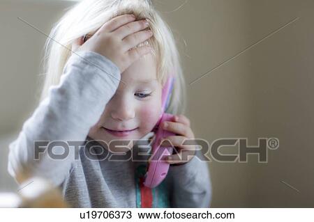 Stock Image - Toddler playing with toy phone. Fotosearch