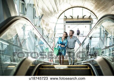 Tourist couple moving up escalator in shopping mall, Dubai, United Arab Emirates View Large Photo Image Stock Image - Tourist couple moving up escalator in shopping mall, Dubai, United Arab Emirates. Fotosearch