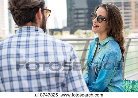 Stock Photography - Tourist couple on waterfront talking, Dubai, United Arab Emirates. Fotosearch