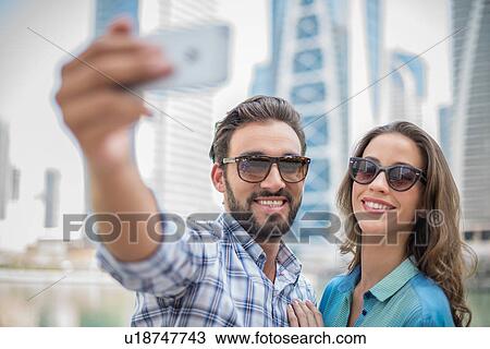 Stock Image - Tourist couple taking smartphone selfie, Dubai, United Arab Emirates. Fotosearch