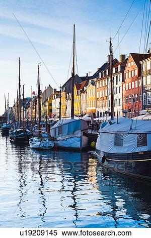 Stock Photography - Traditional multi-coloured townhouses and moored boats on canal waterfront, Copenhagen, Denmark. Fotosearch