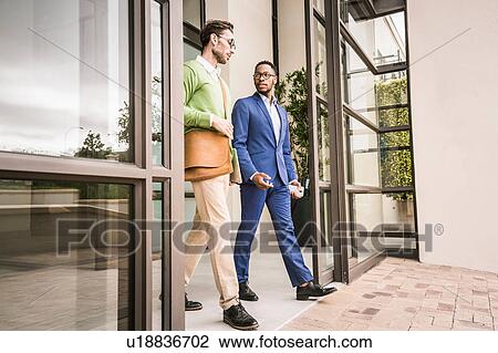Two businessmen having discussion whilst leaving office building View Large Photo Image Stock Image - Two businessmen having discussion whilst leaving office building. Fotosearch