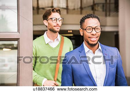 Two businessmen leaving office building View Large Photo Image Stock Photograph - Two businessmen leaving office building. Fotosearch
