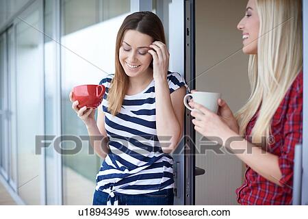 Stock Photography - Two female friends, drinking coffee, outdoors. Fotosearch