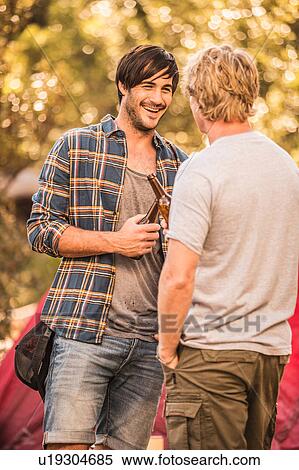 Stock Photography - Two male campers drinking beer in forest, Deer Park, Cape Town, South Africa. Fotosearch