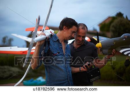 Two male friends holding remote control planes, looking at smartphone View Large Photo Image Stock Photograph - Two male friends holding remote control planes, looking at smartphone. Fotosearch