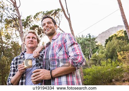 Picture - Two male hikers having coffee in forest, Deer Park, Cape Town, South Africa. Fotosearch