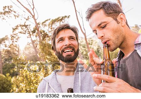 Two men blowing into beer bottle whilst camping in forest, Deer Park, Cape Town, South Africa View Large Photo Image Stock Image - Two men blowing into beer bottle whilst camping in forest, Deer Park, Cape Town, South Africa. Fotosearch