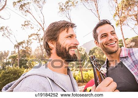 Stock Image - Two men relaxing with beer in forest, Deer Park, Cape Town, South Africa. Fotosearch