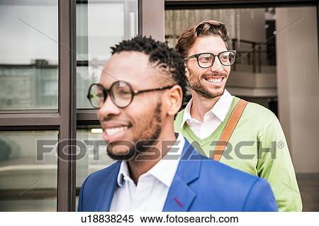 Stock Photography - Two smiling businessmen leaving office building. Fotosearch