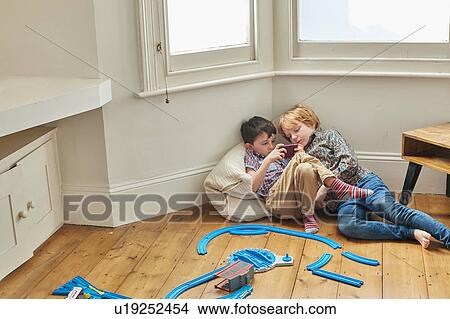 Two young boys, sitting indoors, looking at smartphone View Large Photo Image Picture - Two young boys, sitting indoors, looking at smartphone. Fotosearch