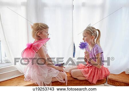 Two young girls, in fancy dress, sitting face to face View Large Photo Image Stock Image - Two young girls, in fancy dress, sitting face to face. Fotosearch