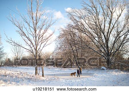 Stock Image - Two young girls with dog in snowy landscape. Fotosearch