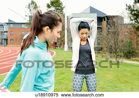 Stock Photography - Two young women outdoors, exercising, stretching. Fotosearch