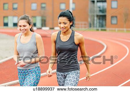 Stock Photo - Two young women walking along running track. Fotosearch