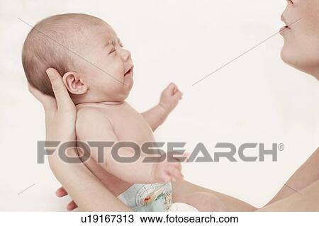 Stock Image - Upset baby being soothed by her mother. Fotosearch