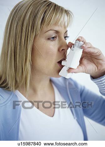 Stock Image - Using asthma inhaler. Fotosearch