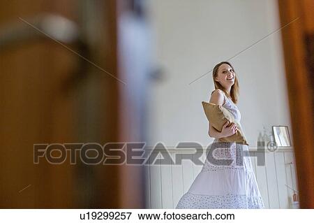 View through gap in doorway of woman holding cushion looking at camera smiling View Large Photo Image Stock Photo - View through gap in doorway of woman holding cushion looking at camera smiling. Fotosearch