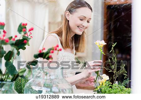View through glass of woman arranging flowers looking down smiling View Large Photo Image Stock Photo - View through glass of woman arranging flowers looking down smiling. Fotosearch