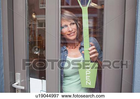 View through glass shop door of woman holding open sign View Large Photo Image Stock Photo - View through glass shop door of woman holding open sign. Fotosearch