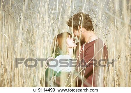 View through tall grass of couple face to face hugging, smiling View Large Photo Image Stock Photo - View through tall grass of couple face to face hugging, smiling. Fotosearch