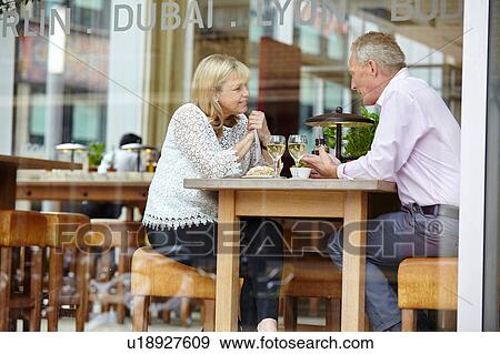 Window view of mature dating couple chatting at restaurant table View Large Photo Image Stock Photo - Window view of mature dating couple chatting at restaurant table. Fotosearch