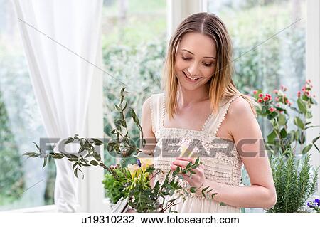 Woman arranging flowers looking down smiling View Large Photo Image Stock Image - Woman arranging flowers looking down smiling. Fotosearch
