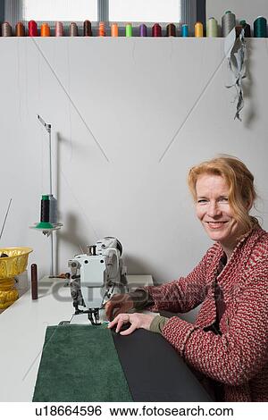 Stock Photograph - Woman at sewing machine looking at camera smiling. Fotosearch