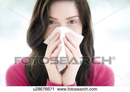 Stock Image - Woman blowing her nose. Fotosearch