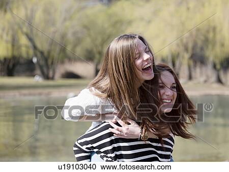 Woman giving laughing friend piggy back View Large Photo Image Stock Image - Woman giving laughing friend piggy back. Fotosearch