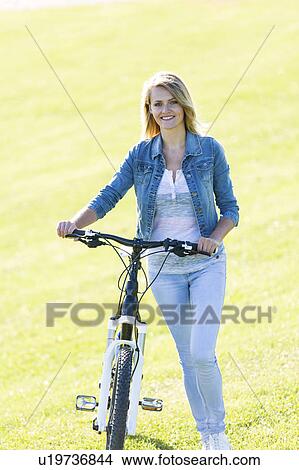Woman holding a bicycle View Large Photo Image Picture - Woman holding a bicycle. Fotosearch