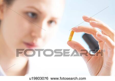Stock Photograph - Woman holding a capsule, close up. Fotosearch