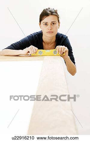 Stock Image - Woman holding a spirit level. Fotosearch
