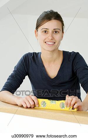 Stock Photo - Woman holding a spirit level. Fotosearch