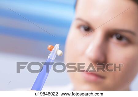 Stock Image - Woman holding tablet with tweezers. Fotosearch