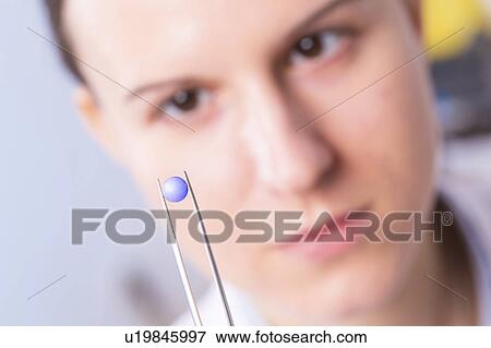 Stock Photo - Woman holding tablet with tweezers. Fotosearch