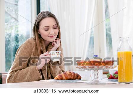 Stock Photography - Woman holding teacup eyes closed smiling. Fotosearch
