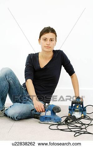 Stock Image - Woman holding wood sanders. Fotosearch