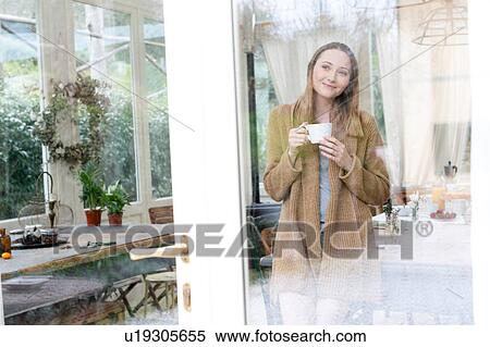 Woman in conservatory holding coffee cup looking away smiling View Large Photo Image Stock Photography - Woman in conservatory holding coffee cup looking away smiling. Fotosearch