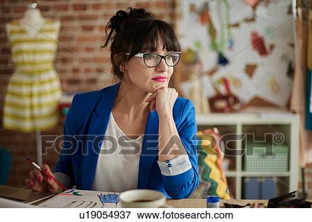 Woman in design studio, hand on chin, looking away View Large Photo Image Stock Photo - Woman in design studio, hand on chin, looking away. Fotosearch