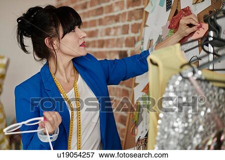 Stock Photo - Woman in design studio looking at wall mounted mood board. Fotosearch