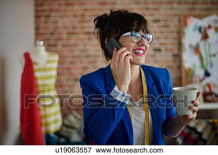Woman in design studio making telephone call looking away smiling View Large Photo Image Stock Photo - Woman in design studio making telephone call looking away smiling. Fotosearch