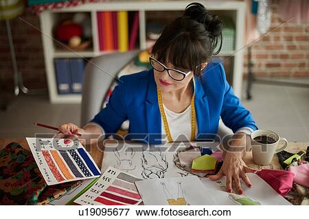 Woman in design studio sitting at desk looking at colour swatches View Large Photo Image Stock Photo - Woman in design studio sitting at desk looking at colour swatches. Fotosearch