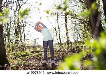 Woman in forest arms raised bending over sideways stretching View Large Photo Image Stock Image - Woman in forest arms raised bending over sideways stretching. Fotosearch