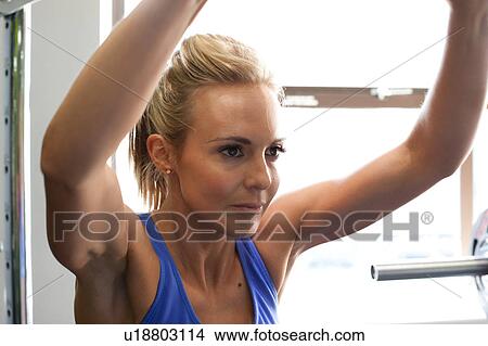 Woman in gym using exercise machine View Large Photo Image Picture - Woman in gym using exercise machine. Fotosearch