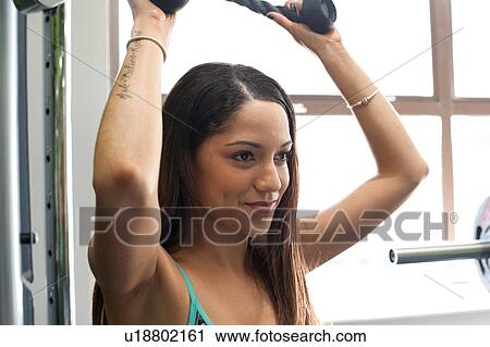Woman in gym using exercise machine View Large Photo Image Stock Image - Woman in gym using exercise machine. Fotosearch