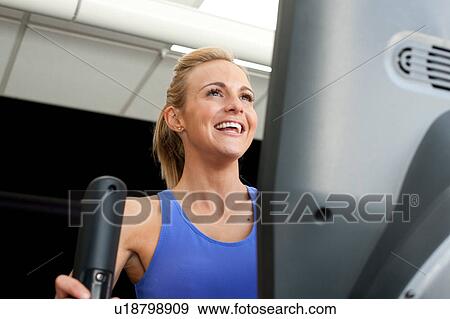 Woman in gym using exercise machine smiling View Large Photo Image Stock Photo - Woman in gym using exercise machine smiling. Fotosearch