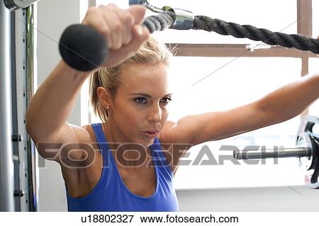 Woman in gym using exercise machine View Large Photo Image Stock Photo - Woman in gym using exercise machine. Fotosearch