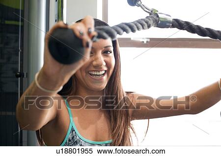 Woman in gym using exercise machine looking at camera smiling View Large Photo Image Stock Photography - Woman in gym using exercise machine looking at camera smiling. Fotosearch